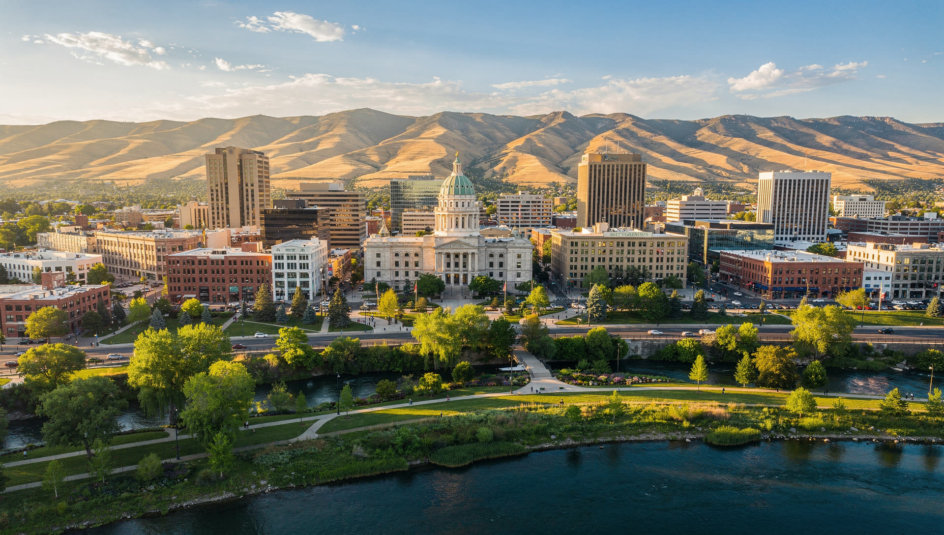 Aerial view of Boise at golden hour, the downtown skyline along the Boise River with the foothills rising to the northeast and the valley opening west.